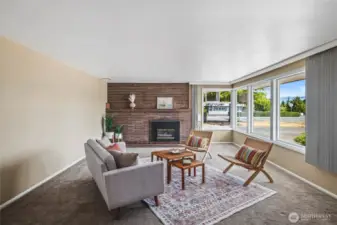 Large living room, brick fireplace, with big windows for lots of light.