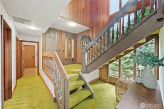 The welcoming lower-level entry showcases the home’s striking split staircase. This level connects the private Primary Suite, additional bedrooms, and convenient side-door access to the outdoor patio and shed.