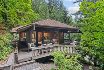 The expansive deck offers multiple seating areas and a graceful stairway leading to the lower level and garden, serving as a stunning centerpiece for both entertaining and relaxation.