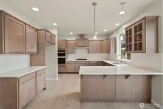 Sleek and modern kitchen with Quartz counters and full tile backsplash. Pendant lights hang above eating bar are perfect for casual meals or entertaining.