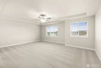 Spacious primary bedroom with carpet flooring creating a soft and calming atmosphere. A ceiling fan with an integrated light fixture is mounted at the center of the ceiling, providing both illumination and airflow.