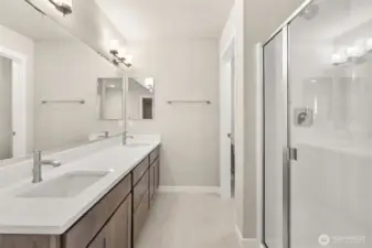 Primary bathroom with tile flooring and quartz countertops.