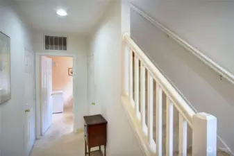 Hardwood entry transitions to Travertine flooring in the hall off the garage and into the laundry room with a laundry tub. Notice the door on right for storage. Stairs to upper main living area.