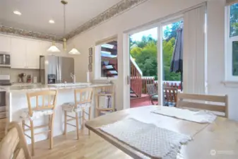 Kitchen from nook area showing breakfast bar, deck and stairs to upper deck.  There is storage off the deck as well.