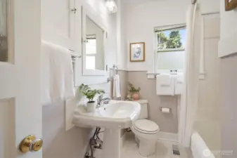The main floor bathroom has a wonderful tub and storage tucked in behind the door.