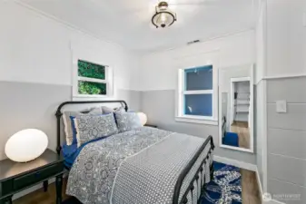 One of the serene bedrooms inside 7316 Eastside Drive NE. This coastal retreat pairs cottage charm with clean lines and restful tones—perfect after a day on the water. White wainscoting, natural light, and clever built-ins complete the calming space.