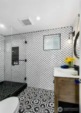 Sleek design and artisanal details define this spa-like bath at 7316 Eastside Drive NE. A walk-in shower with frameless glass, striking patterned tilework, and custom finishes elevate everyday routines in the Beach House. Coastal comfort meets curated style.