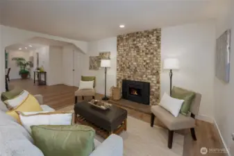 Sunny living room with wood burning fireplace, all new vinyl plank flooring and interior paint.