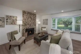 Sunny living room with wood burning fireplace, all new vinyl plank flooring, interior paint plus newer windows and blinds throughout.