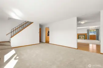 Living room with access to the stairs, hallway and kitchen in two different places.