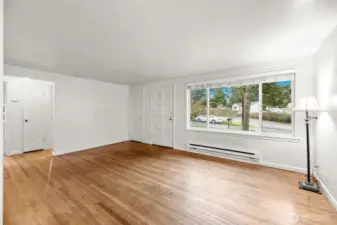Second view of the living room showcasing the large picture window and beautiful hardwood floors.