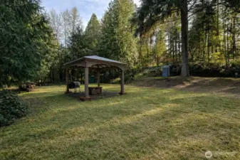 Expansive grassy area with gazebo and fire pit, ideal for outdoor entertaining and relaxation.