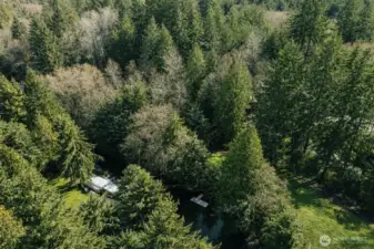 Expansive aerial perspective showcasing the property’s serene, wooded setting along the scenic canal.