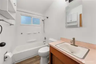 This functional full bathroom features a tub/shower combo, updated faucet, overhead storage, and a large frosted window that brings in soft natural light while maintaining privacy. Simple and efficient with everything you need.