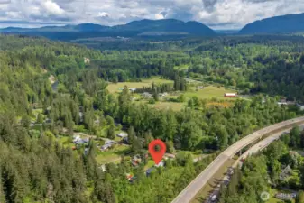 Surrounded by natural beauty! Aerial view shows proximity to Cedar River, quiet roads, and scenic forested backdrop.
