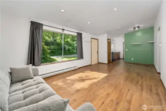 Natural light pours into the open living and dining space through the large picture window, creating a warm and welcoming atmosphere. The layout flows seamlessly into the kitchen, offering flexibility for everyday living or entertaining.