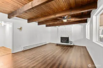 Lower level rec room with open beam ceiling and woodstove insert