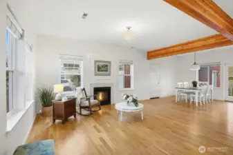 A grand open floorplan with hardwoods, exposed beam ceiling detail, and a gas fireplace offering a warm and inviting retreat.