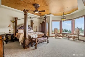 Primary Suite with recessed faux painted ceilings, sitting area overlooking the the pool, and patio door access to the pool and hot tub. There is a cozy fireplace with overhead recessed TV.