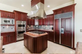 The custom dark cherry cabinets are soft-close, and have easy glide pull-out drawers. The chef's kitchen also includes Viking double ovens with additional pull-out warming drawer, and a Viking gas 6-cooktop stove