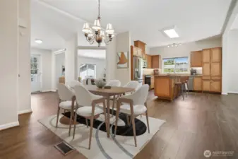 Formal dining room opens to kitchen and the family room, features vaulted ceilings and vinyl plank flooring.  Virtually staged photo.