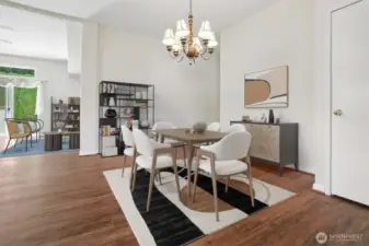 Formal dining room opens to kitchen and the family room, features vaulted ceilings and vinyl plank flooring.  Virtually staged photo.