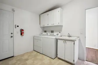 Laundry room with full size washer and dryer, utility sink and access to the attached 2 car oversized garage and workshop.