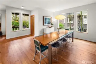 The dining area is wrapped in windows on two sides, with views into the backyard and direct access to the rear deck through the wood-trimmed door.