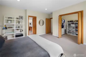 Taken from the bed wall looking toward the room's opposite side, this view reveals  two doorways — one leading to the en-suite bathroom, visible in the background, and one opening directly to the walk-in closet.
