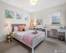 A bright and comfortable secondary bedroom with treetop views — equally suited for rest or study.