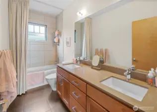 The shared upper level bathroom features a double vanity, soaking tub with tile surround, and generous counter space for busy morning routines.