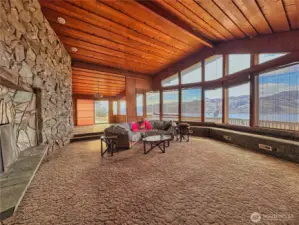 Rock wall fireplace, vaulted wood ceilings give warmth and texture and wall of windows to water and mountain views extend serenity