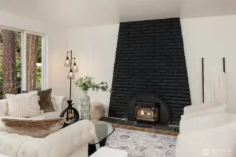 Open living room with large windows and gas fireplace.