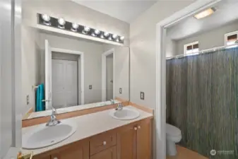 Guest bathroom with double sinks & tile flooring.