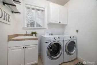 Good-sized laundry room offers a utility sink and storage.  Tile floors.