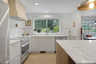 All-new appliances and cabinetry pair beautifully with marble surfaces, creating a clean, elevated look. The kitchen window frames a peaceful view of the backyard—perfect for keeping an eye on kids and pets at play while you cook and gather.