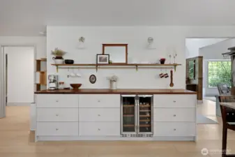 A custom coffee and wine bar adds both style and function, featuring ample storage, display shelving, and a built-in beverage fridge. Thoughtfully positioned, the entry is just to the right, while a door to the left leads to the main-level bonus room—offering flexibility for guests, work, or additional living space.