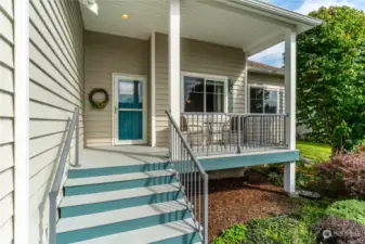 Covered front entry with bistro table and 2 chairs, storm glass door and a beautiful front door with accent glass!