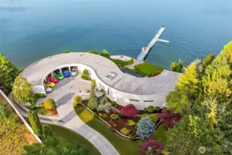 From above, the S House reveals its sculptural form — a sweeping arc that cradles a 6-bay showcase garage and embraces Wollochet Bay. Impeccably landscaped grounds flow to a private deepwater dock, ready to welcome a 60-foot yacht