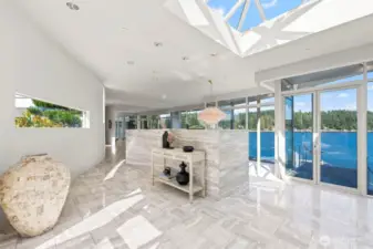 Step inside to a sunlit foyer where marble floors, sculptural lines, and expansive glass immediately frame Wollochet Bay’s blue expanse — a striking prelude to this architectural icon