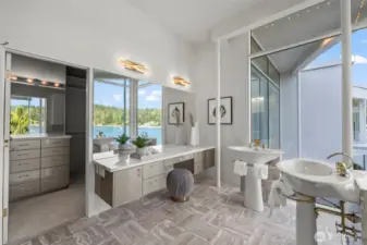 Dual pedestal sinks, a spacious vanity with marble and lucite, and a walk-in closet with washer/dryer create a primary bath that’s as functional as it is glamorous.