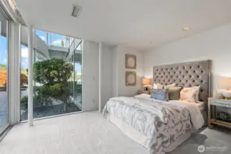 Another fantastic guest room with a soft neutral palette as the windows frame lush garden and water views