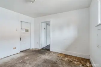 Living Room with bedroom door to the left and kitchen to the right of it.