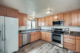 Solid slab countertops, Frigidaire fridge, LG stainless steel appliances, smooth-top stove, honey cabinets extend to the ceiling with matching crown molding. Complimentary laminate flooring offers quick clean-up