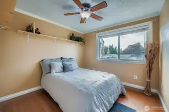 Bedroom #2 with wood flooring, shelving, ceiling fan, closet with built-in shelves and overlooks front of home
