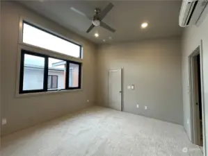 Large primary bedroom with en suite, walk-in closet, ceiling fan with light and vaulted ceiling.