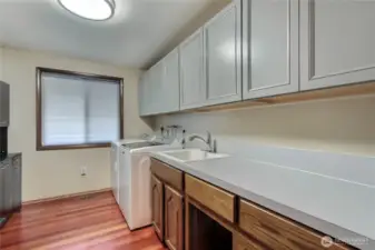The laundry room has tons of space, with an abundance of cabinets and counters plus a laundry sink.
