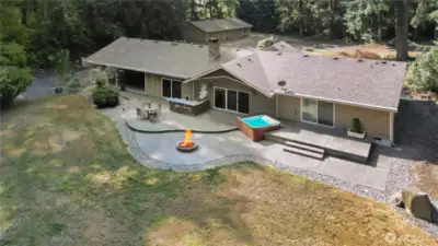 Aerial shows outdoor kitchen, large patio, deck, and fire pit.
