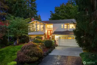Nestled in a lush, park-like setting, this beautifully maintained home shines with warm evening glow and timeless curb appeal. Expansive picture windows flood the interior with natural light, while vaulted ceilings and a striking mid-century flair add a sense of openness and style. Mature landscaping frames the entry, creating a private oasis just minutes from town conveniences. Enjoy the inviting front porch, spacious driveway, and beautifully lit architectural lines that highlight the home’s welcoming character. Ideal for those who appreciate serenity, space, and thoughtful design in a prime location! ????