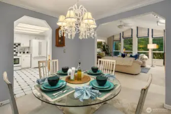 The open flow between dining, living, and kitchen spaces makes entertaining effortless. Crisp white trim, crown molding, and a statement chandelier add timeless charm, while the layout keeps every conversation connected from the table to the firelit living room.